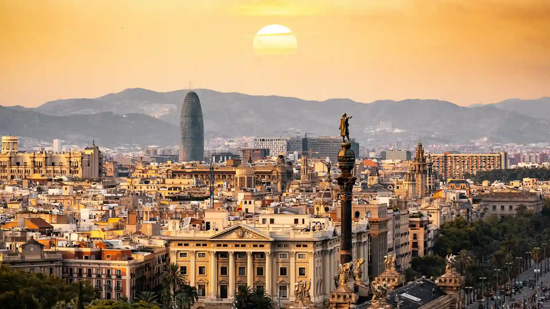 A panoramic view of Barcelona at sunset, showcasing vibrant colors illuminating the skyline and iconic architecture.