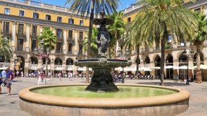 A fountain surrounded by palm trees in a vibrant plaza, creating a serene and inviting atmosphere.